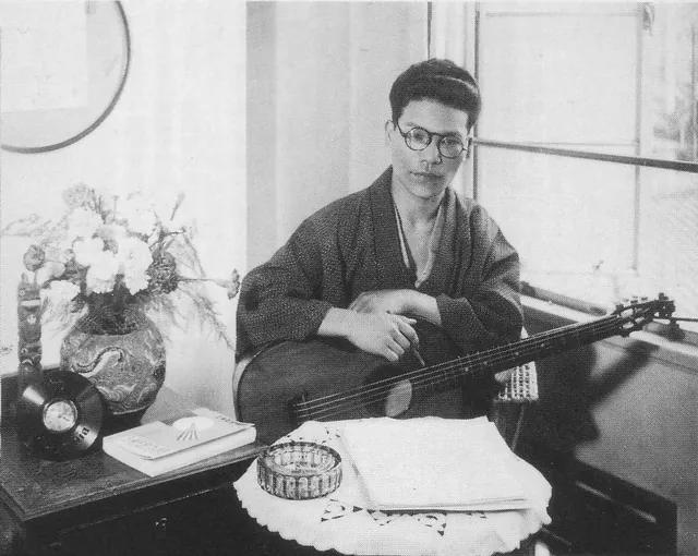 1931 年的古賀政男,懷裡抱著一把吉他;他 1948 年親手彈吉他伴奏的〈湯の町エレジー〉,後來成了台語歌〈溫泉鄉的吉他〉。