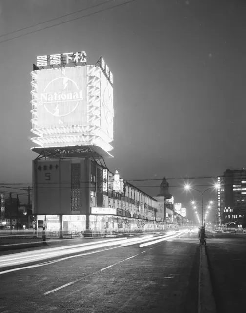 1960 年代台北中華商場夜景,家電品牌的巨型霓虹招牌高掛;這裡是當年民眾選購電子零件與唱片的地方,也是電視走進家庭的年代