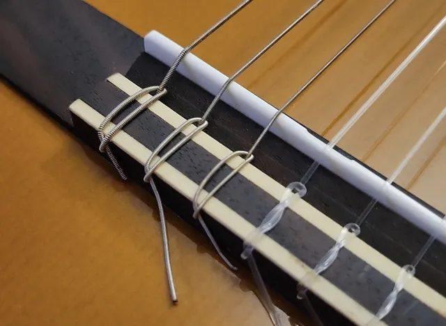 古典吉他低音弦在琴橋上打結的樣子,可以清楚看到一圈一圈纏在芯外的金屬線