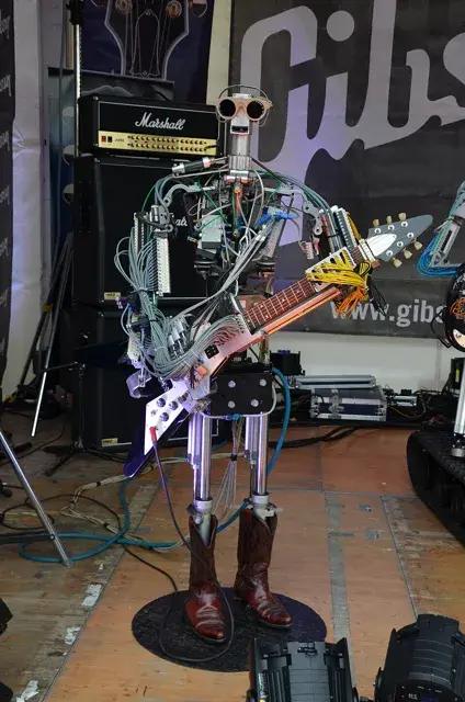 機器人樂團 Compressorhead 的吉他手「Fingers」抱著 Flying V,2013 年法蘭克福樂器展。