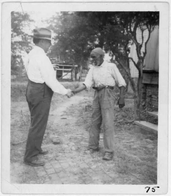 1940 年民謠採集者約翰·洛馬克斯在阿拉巴馬州和一位靈歌歌手握手,他和兒子艾倫帶著錄音機走進南方監獄,留下大量獄中歌聲。