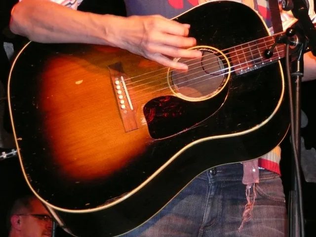 2008 年英國雪菲爾一場演出的舞台上,一把 Gibson J-45 的音孔裡卡著磁性拾音器(照片原檔註明另接 Fishman 前級);音孔上的磁鐵,到今天仍在舞台上使用
