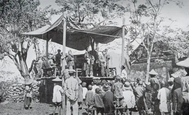 約 1930 年出版的《日本地理大系・臺灣篇》中的野台戲照片,寺廟前臨時搭起戲台,觀眾免費觀看