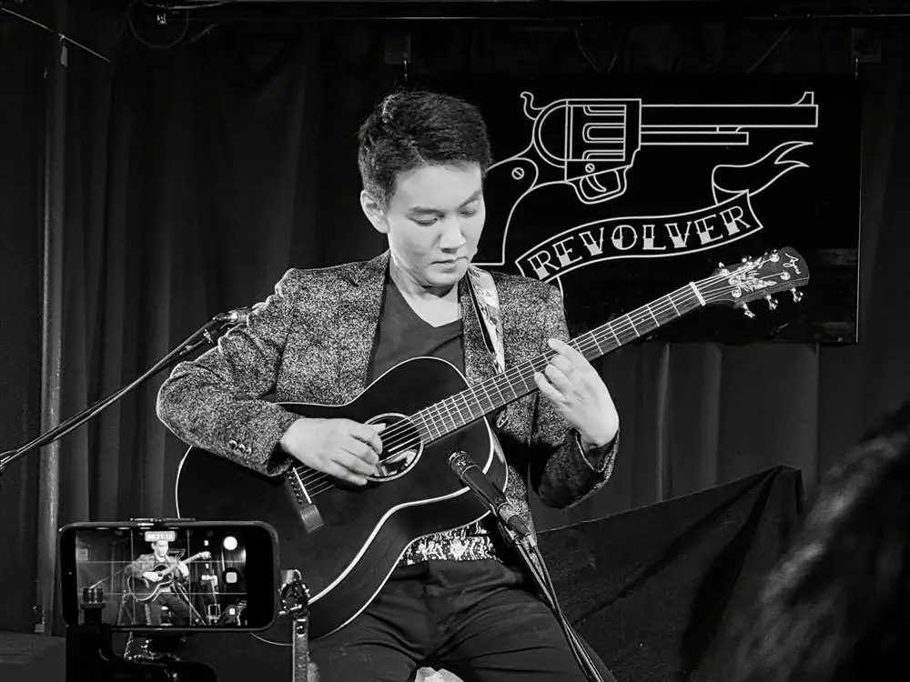 盧家宏抱著木吉他在台北 REVOLVER 演奏